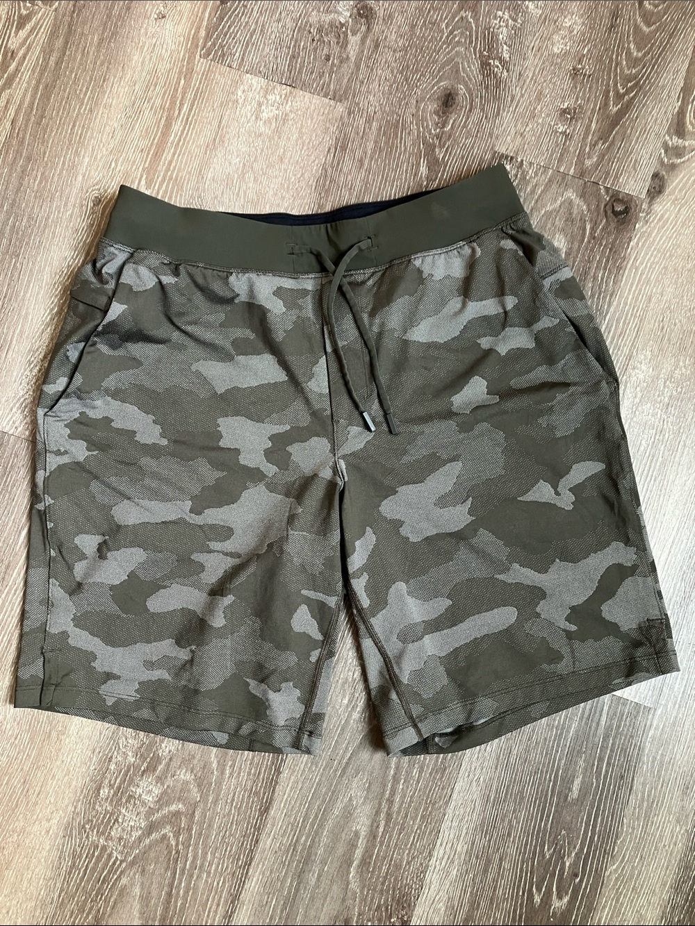 Lululemon Atletica T.H.E. Shorts in a dark olive green camouflage pattern.